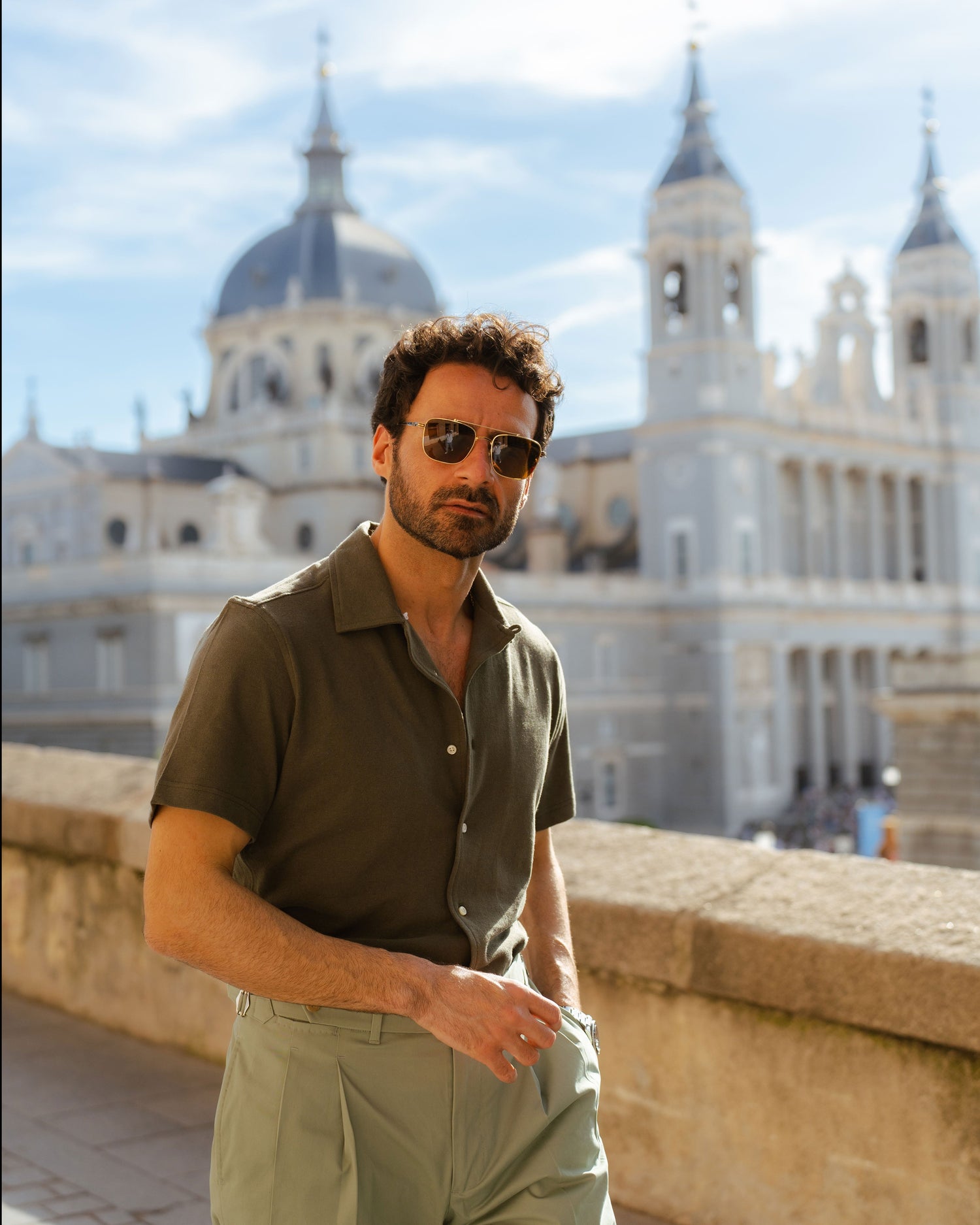 Model outside wearing mens custom polo cotton camp shirt by Luxire in olive green hand in pocket 4