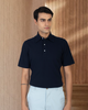 Model wearing the custom oxford polo shirt for men by Luxire in navy with white pants